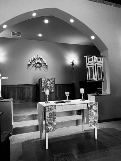 Anglican Church altar with chalice, candles, and pulpit beneath an arched ceiling in a small chapel.